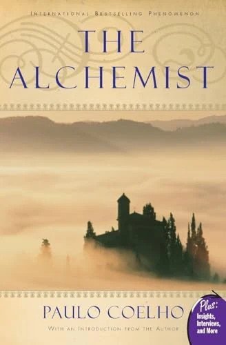 Cover of Paulo Coelho's 'The Alchemist' featuring a misty landscape with a castle and cypress trees, inspiring travel and adventure.