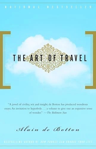 Cover of 'The Art of Travel' by Alain de Botton featuring a blue sky with clouds and elegant gold accents.