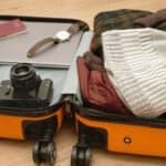Open suitcase filled with winter clothing, accessories, and travel essentials for a winter getaway.