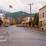 Scenic view of Etna's historic Main Street with small shops, American flags, and mountain backdrop in California's tiny mountain town.