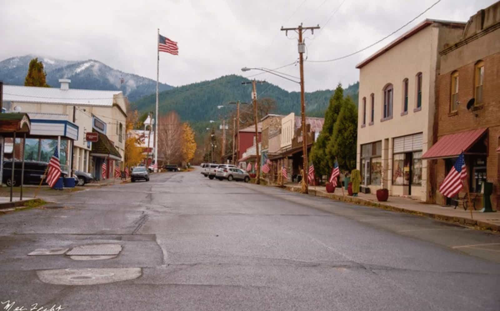 Scenic view of Etna's historic Main Street with small shops, American flags, and mountain backdrop in California's tiny mountain town.